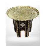 A Syrian mother of pearl-inlaid table with later engraved brass top, diameter 58cm.