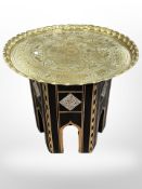 A Syrian mother of pearl-inlaid table with later engraved brass top, diameter 58cm.