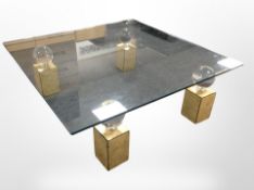 A large contemporary square glass coffee table on gilt pedestal supports, width 120cm x height 39cm.