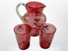 A Victorian cranberry glass and gilted jug, together with two similar beakers, tallest is 17cm.