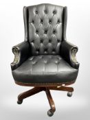 A contemporary Chesterfield-style swivel armchair in black buttoned vinyl.