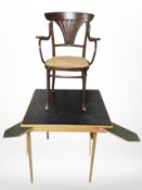 A black vinyl-topped square folding card table and a beech bergere armchair.