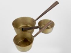 Three 19th century graduated brass pans, with cast iron handles,