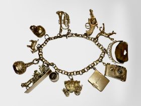 A 9ct gold charm bracelet with many charms including skull, horse and carraige, revolver, camera,