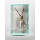 A polished rock crystal pendant on silver gilt chain.