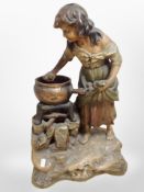 A painted chalk figure of a woman cleaning a cast iron cooking pot,
