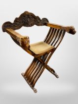 A carved beech Savonorola style armchair with lion mask arm rests,