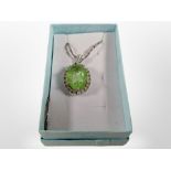 A silver pendant on chain with faceted lime green stone.
