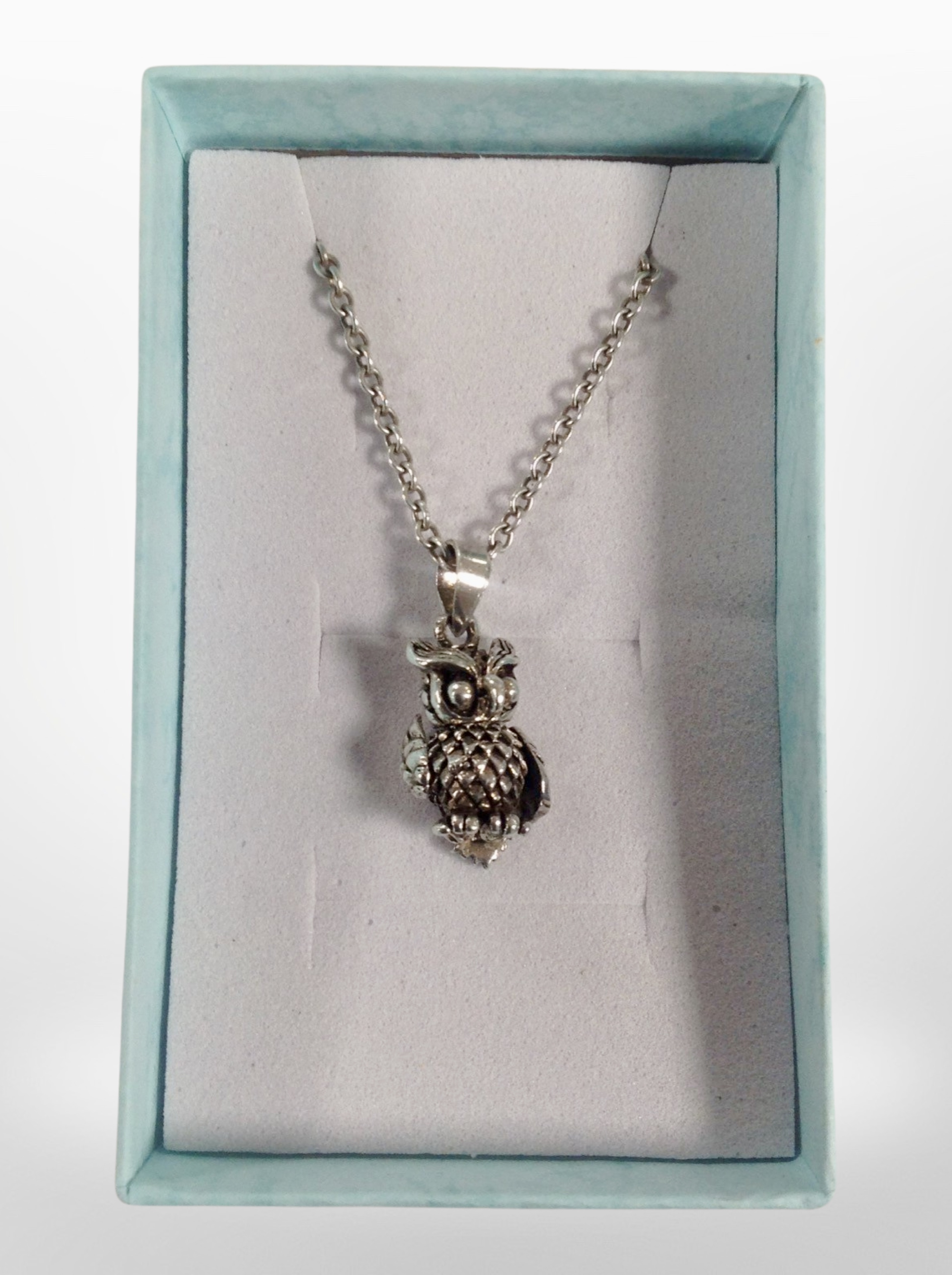 An articulated silver owl pendant on chain.