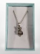An articulated silver owl pendant on chain.