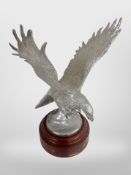 A silvered metal eagle on turned wooden plinth, height 23cm.