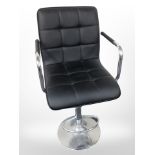 A contemporary black stitched leather rise and fall swivel armchair on chrome support