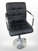 A contemporary black stitched leather rise and fall swivel armchair on chrome support