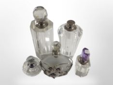 Four faceted crystal perfume bottles, and a further frosted glass bottle in metal casing,