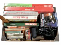 A box of assorted board games, volumes, Bandmaster mouth organ, Canon camera,