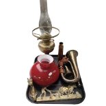 A brass oil lamp with red glass shade, together with a brass bugle, two coat racks,