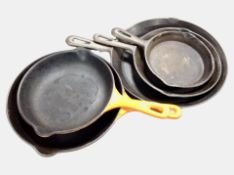 Three graduated cast-iron skillets, longest 37cm, together with two Le Creuset enameled skillets.