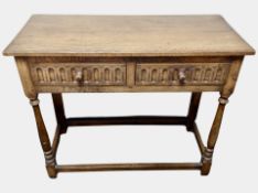 A reproduction carved oak two drawer side table, with plate glass top,