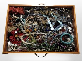 A wooden drawer containing assorted costume jewellery, bead necklaces, bracelets, etc.