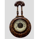 A heavily carved beech barometer, length 43cm.