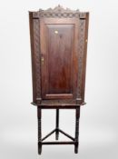 A 19th century carved oak triangular corner cabinet on bobbin turned stand,
