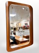 A 1970's curved and laminated teak framed mirror,