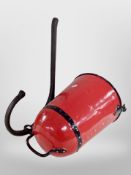 A red painted fire bucket with cast iron wall mounting bracket