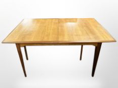 An Alfred Cox teak extending dining table fitted a leaf,