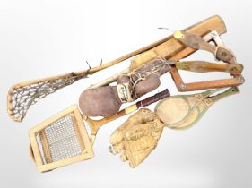 A group of vintage sports equipment including tennis racket, lacrosse stick, cricket bat,