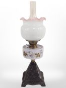 An oil lamp with cast metal support and hand painted opaque glass reservoir,