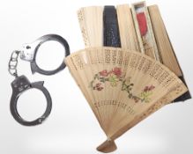 A group of oriental and other hand fans, one in box, together with a pair of handcuffs (no key).