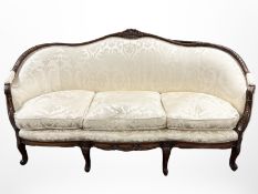 A French carved walnut three seater salon settee in damask upholstery,