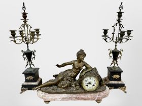 A 19th century French rouge marble and patinated metal clock garniture, striking on a bell,