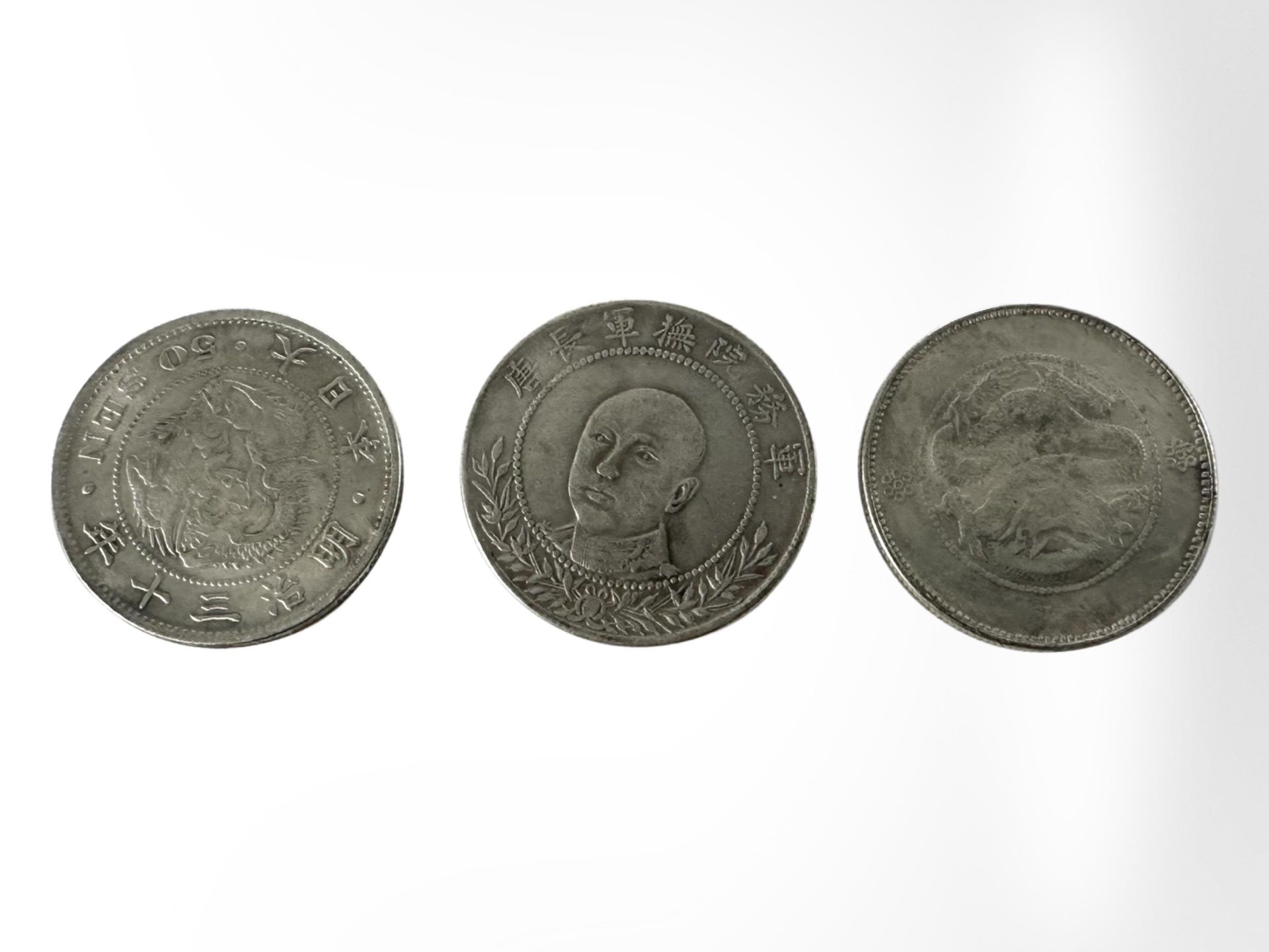 Three Chinese white metal coins.