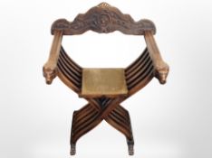 A carved beech Savonarola style armchair with lion mask armrests,