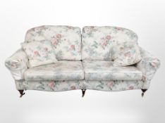 A pair of Victorian style floral upholstered three seater settees on brass castors,