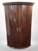 A George III mahogany and pine bow-front hanging corner cabinet,