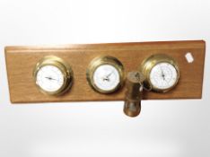A combination thermometer/barometer/hygrometer mounted on oak board,