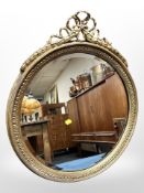 A 20th century gilt gesso circular mirror with ribbon pediment,