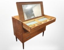A Danish teak four drawer dressing chest with pull out slide and mirrored interior,