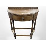 An early 20th century carved oak deni-lune hall table,