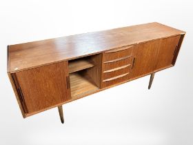 A Danish teak low sideboard fitted with four drawers and sliding cupboard doors,