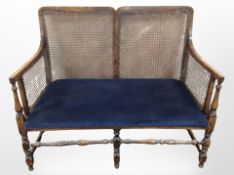 An Edwardian bergere two seater settee in blue upholstery,