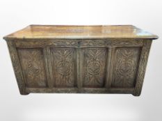 A George III panelled oak coffer with later carving, raised on castors,