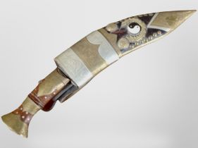 A kukri knife in ornate brass-mounted sheath.