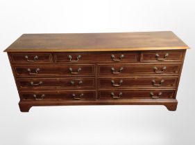 A reproduction yew wood low sideboard, fitted nine drawers,