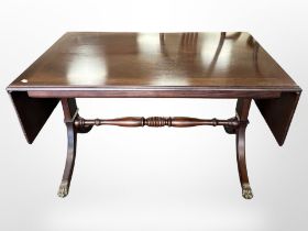 A reproduction mahogany drop leaf coffee table on brass capped feet,