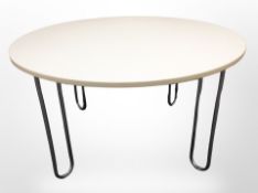 A Scandinavian melamine circular dining table on curved chrome supports,