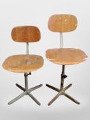 Two 20th century laminated ply and teak swivel chairs on metal supports