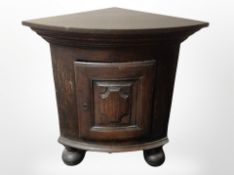 A 19th century Continental stained oak bow fronted corner cabinet on large bun feet,